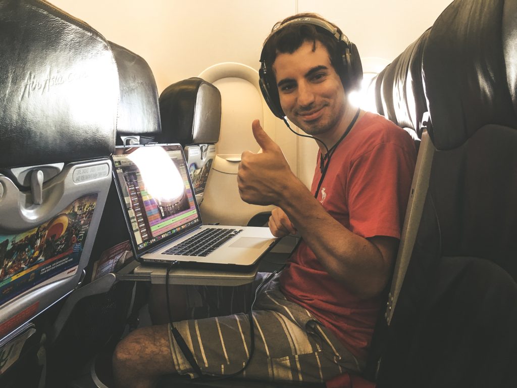 Tom wearing headphones on a plane with his thumbs up